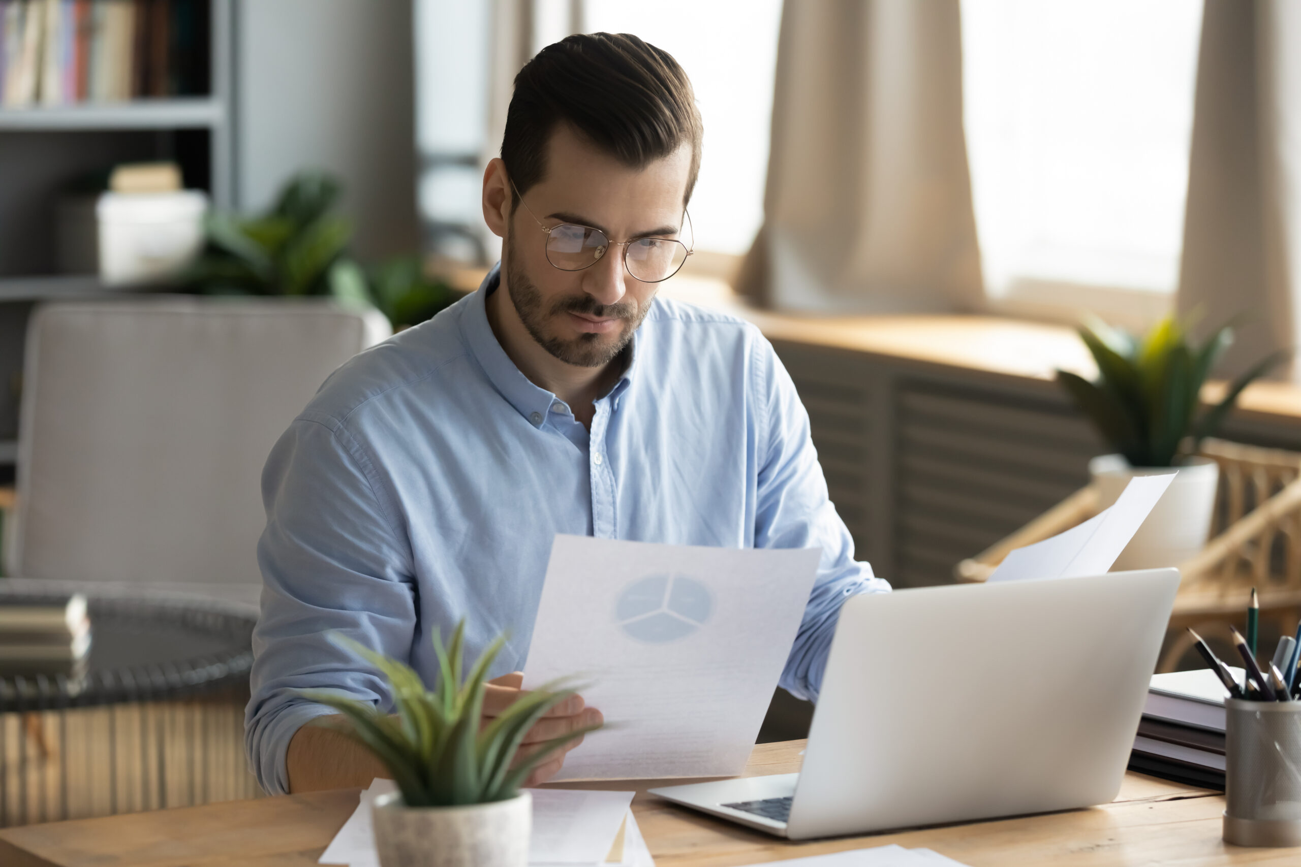 Concentrated young businessman analyzing marketing research report. czy lng jest ważne?