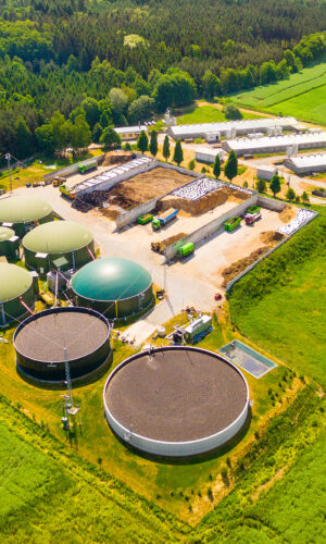 Aerial view over biogas plant and farm in green fields. Renewabl
